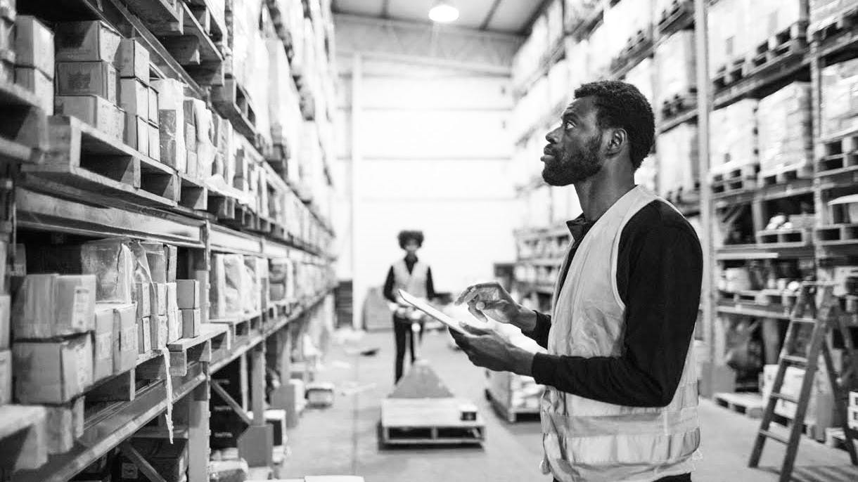 A Black worker checking inventory in a warehouse