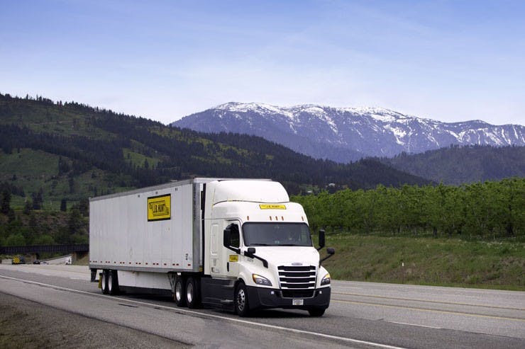A truck driving on a highway in front of a mountain